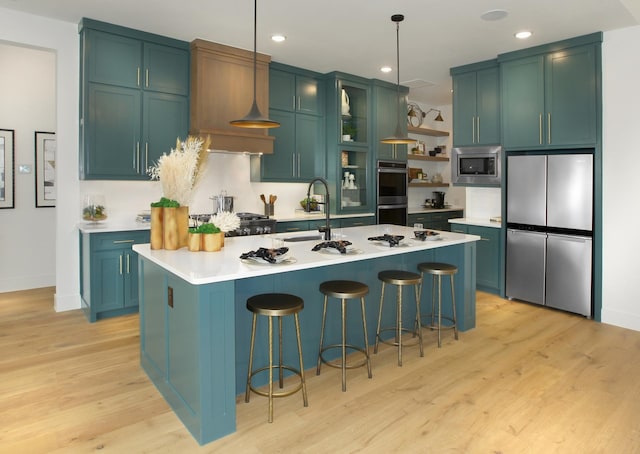 kitchen featuring a breakfast bar, sink, hanging light fixtures, a kitchen island with sink, and stainless steel appliances