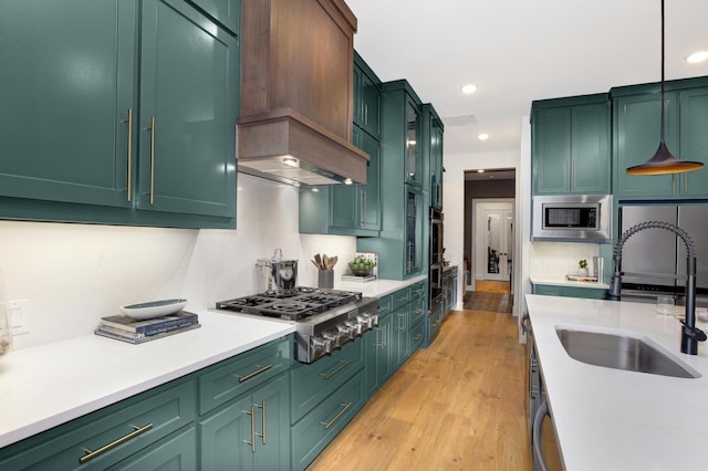 kitchen featuring green cabinetry, stainless steel appliances, sink, and hanging light fixtures