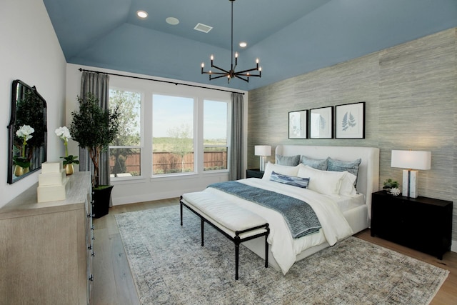 bedroom featuring lofted ceiling, a notable chandelier, and light wood-type flooring