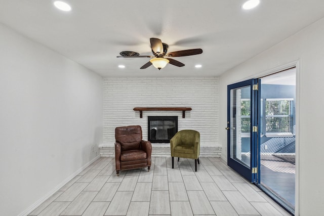 living area with ceiling fan and a fireplace