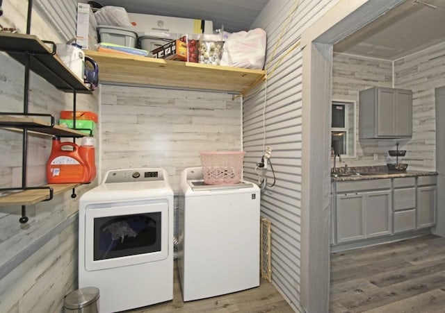 clothes washing area featuring washing machine and dryer, wood walls, and light hardwood / wood-style flooring