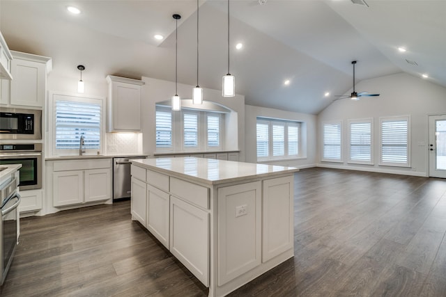 kitchen featuring stainless steel appliances, a sink, a kitchen island, light countertops, and dark wood finished floors