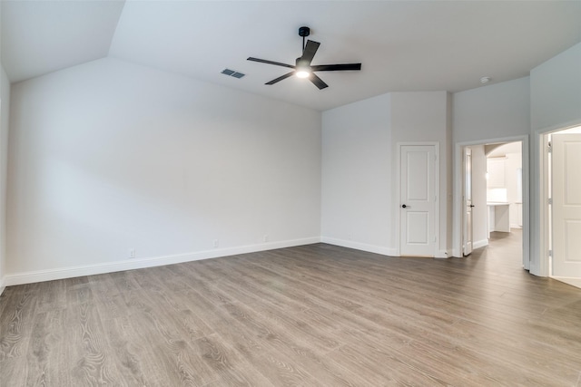 unfurnished room featuring ceiling fan, wood finished floors, visible vents, baseboards, and vaulted ceiling