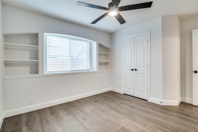 unfurnished bedroom featuring a ceiling fan, a closet, baseboards, and wood finished floors