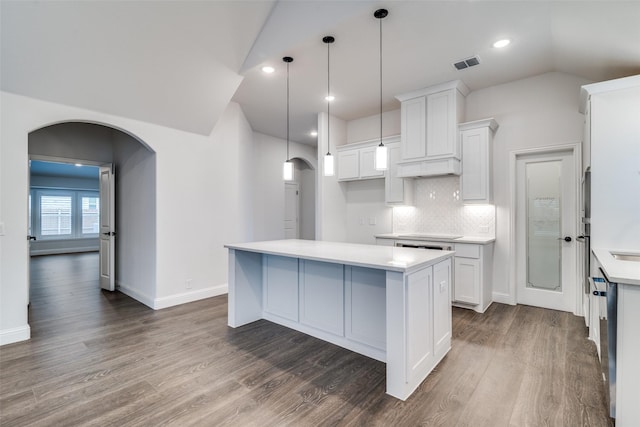 kitchen featuring light countertops, arched walkways, visible vents, and dark wood finished floors