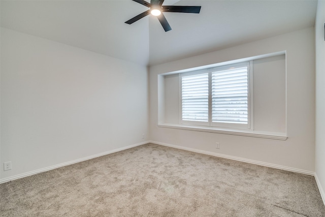 carpeted spare room with a ceiling fan, vaulted ceiling, and baseboards