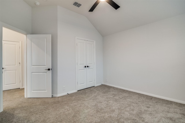 unfurnished bedroom featuring carpet floors, lofted ceiling, a closet, visible vents, and baseboards