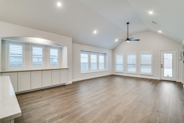 unfurnished living room with lofted ceiling, ceiling fan, visible vents, baseboards, and light wood finished floors