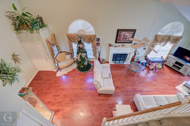 living room featuring hardwood / wood-style flooring, ceiling fan, and a high ceiling