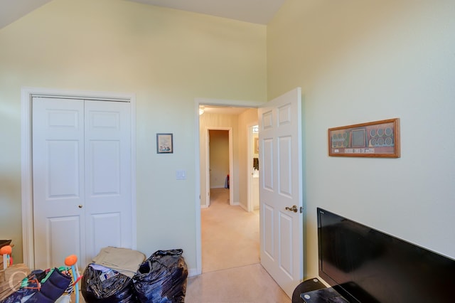 bedroom featuring light carpet, high vaulted ceiling, and a closet