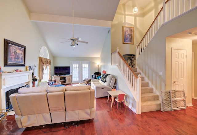 living room featuring beam ceiling, hardwood / wood-style flooring, ceiling fan, and a towering ceiling