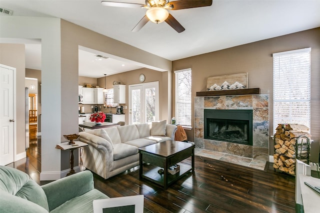 living room featuring a tile fireplace, ceiling fan, and dark hardwood / wood-style flooring