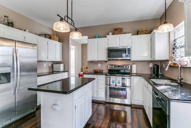 kitchen featuring stainless steel appliances, sink, white cabinetry, a kitchen island, and pendant lighting