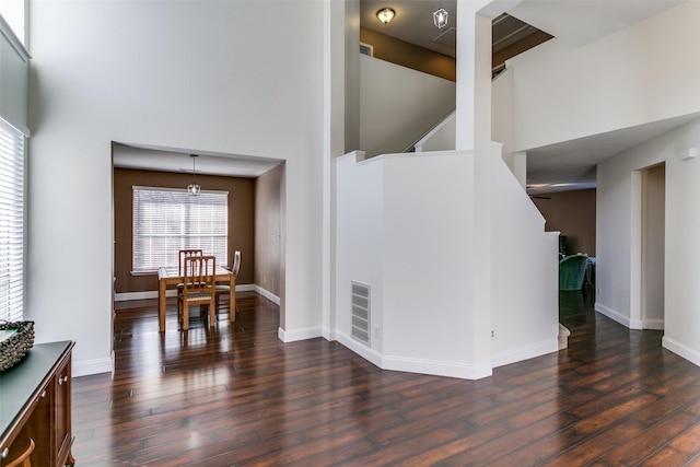 interior space with a towering ceiling and dark hardwood / wood-style flooring