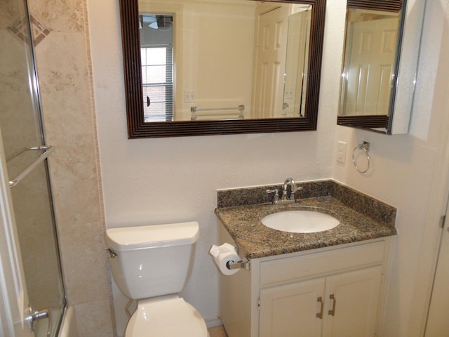 full bathroom with enclosed tub / shower combo, vanity, and toilet