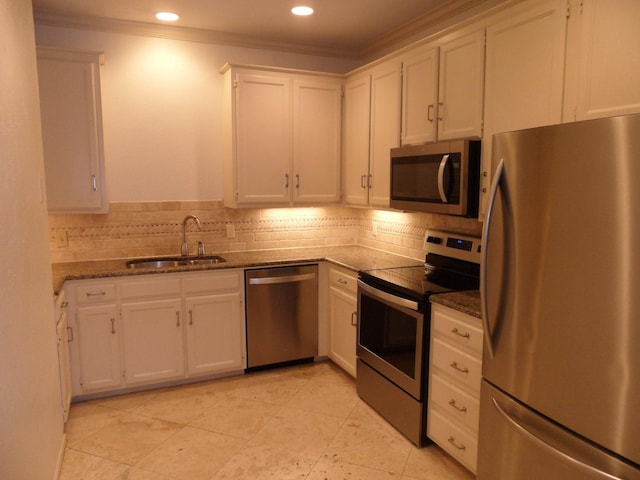 kitchen with sink, dark stone countertops, white cabinets, backsplash, and stainless steel appliances