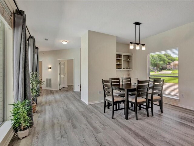 dining area featuring light wood finished floors, baseboards, and visible vents