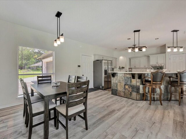 dining space with light wood-type flooring and baseboards