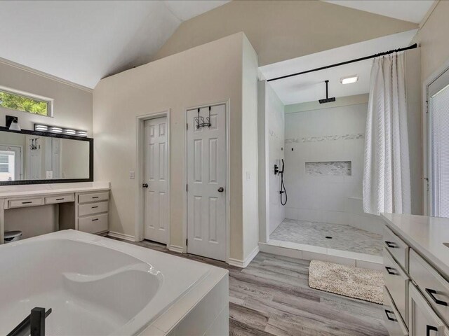 full bath with a tub to relax in, wood finished floors, vanity, vaulted ceiling, and walk in shower