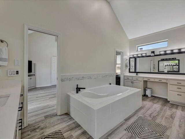 bathroom featuring a garden tub, high vaulted ceiling, wood finished floors, and vanity