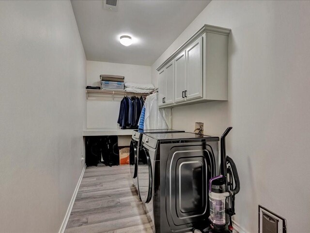 laundry area featuring washer and clothes dryer, visible vents, cabinet space, light wood-type flooring, and baseboards