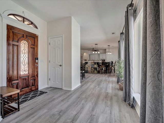 foyer with baseboards, visible vents, and light wood finished floors