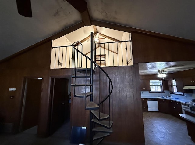 staircase with vaulted ceiling with beams, ceiling fan, sink, and wooden walls