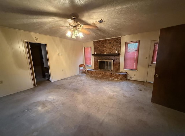 unfurnished living room featuring ceiling fan, a textured ceiling, and a brick fireplace