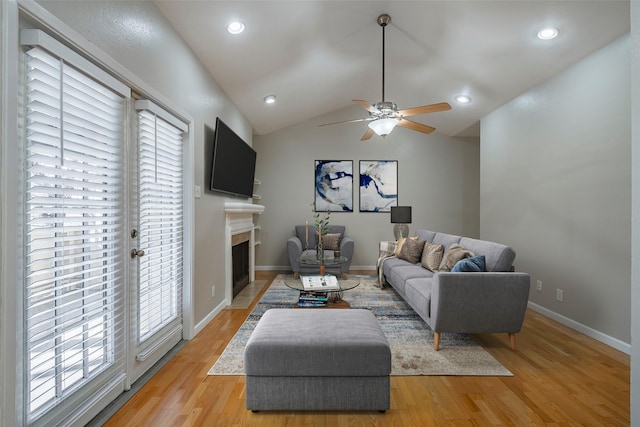 living room with a wealth of natural light, ceiling fan, light hardwood / wood-style flooring, and vaulted ceiling