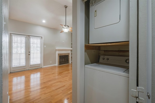 laundry room with stacked washer / drying machine, light hardwood / wood-style floors, and ceiling fan