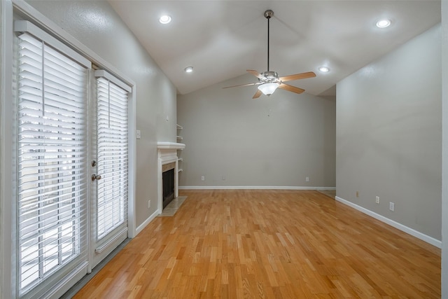 unfurnished living room with light hardwood / wood-style flooring, vaulted ceiling, a wealth of natural light, and ceiling fan