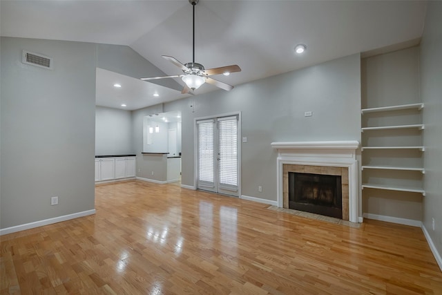 unfurnished living room featuring a tile fireplace, light hardwood / wood-style floors, ceiling fan, and lofted ceiling