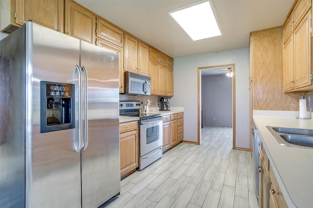 kitchen featuring stainless steel appliances, ceiling fan, light hardwood / wood-style floors, and sink