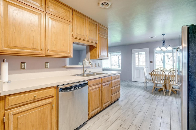 kitchen with light wood-type flooring, stainless steel appliances, sink, decorative light fixtures, and an inviting chandelier