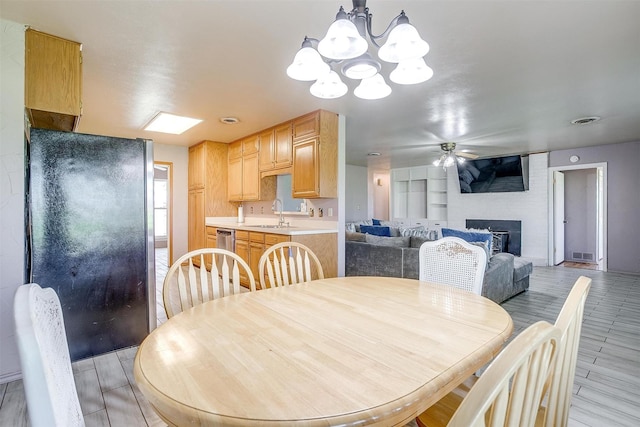 dining space with a fireplace, ceiling fan with notable chandelier, and sink