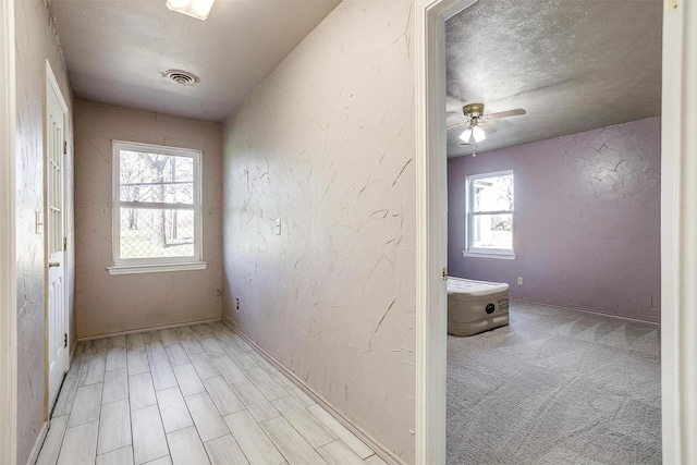 corridor featuring light colored carpet and a textured ceiling