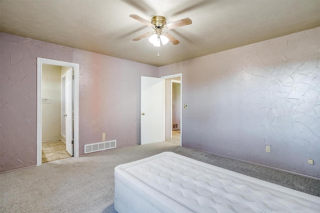 bedroom featuring connected bathroom, light colored carpet, and ceiling fan