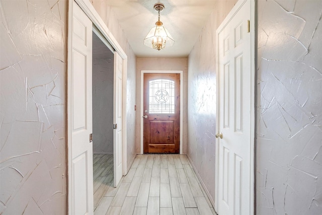 doorway to outside featuring a notable chandelier and light hardwood / wood-style floors