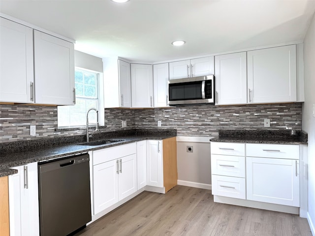 kitchen featuring dark stone countertops, dishwasher, white cabinets, and sink