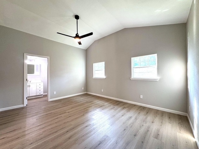 unfurnished bedroom featuring ensuite bathroom, ceiling fan, light hardwood / wood-style floors, and vaulted ceiling