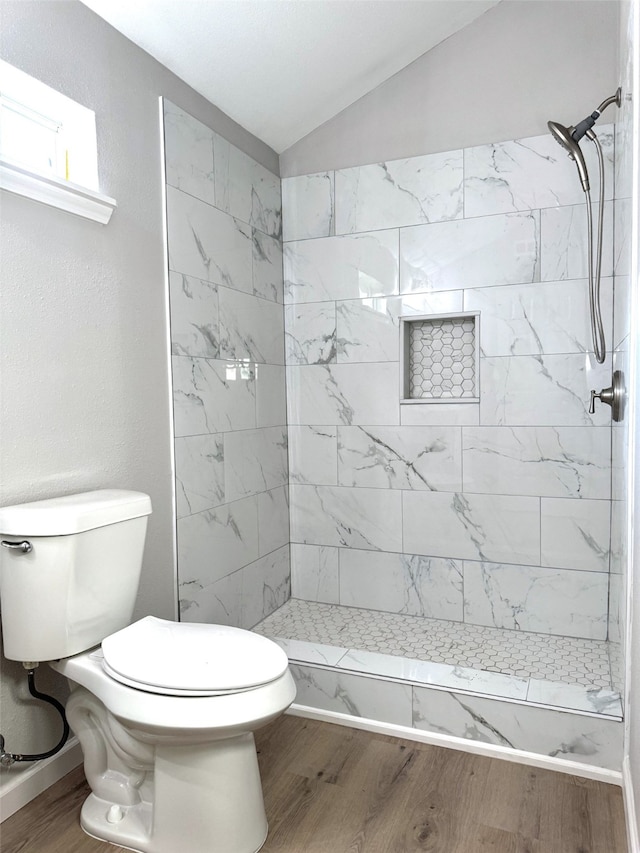 bathroom featuring hardwood / wood-style floors, a tile shower, and toilet