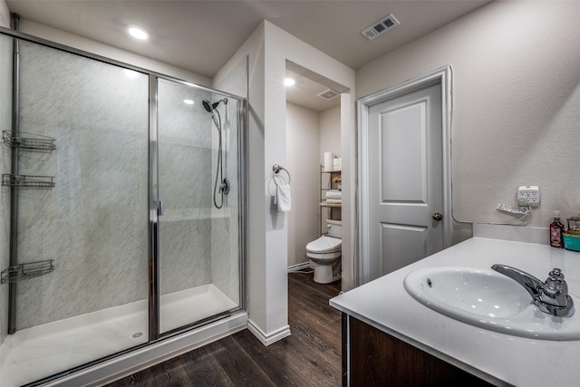 bathroom with hardwood / wood-style flooring, vanity, toilet, and walk in shower