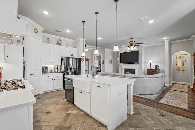 kitchen featuring ceiling fan, sink, pendant lighting, a center island with sink, and white cabinets