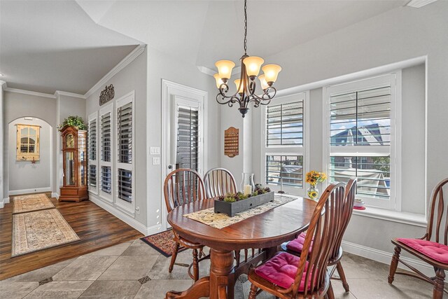 tiled dining space featuring an inviting chandelier, a wealth of natural light, and ornamental molding