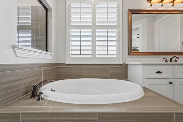 bathroom with tiled tub and vanity