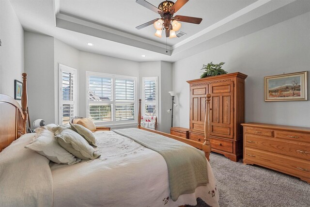 carpeted bedroom featuring ceiling fan, crown molding, and a tray ceiling