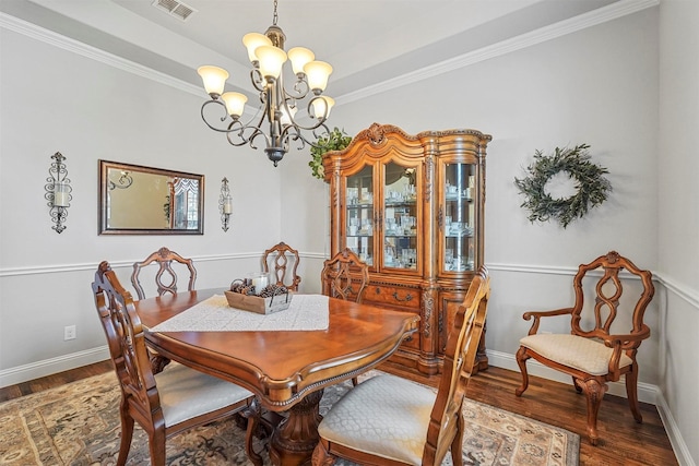 dining room featuring dark wood-type flooring, a tray ceiling, and an inviting chandelier