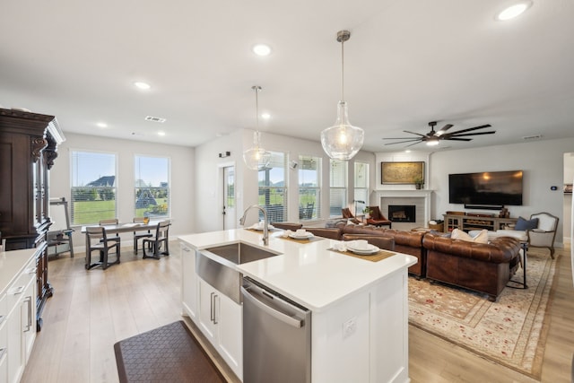 kitchen with pendant lighting, an island with sink, sink, white cabinets, and stainless steel dishwasher