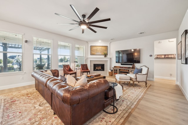 living room with ceiling fan, a fireplace, and light wood-type flooring