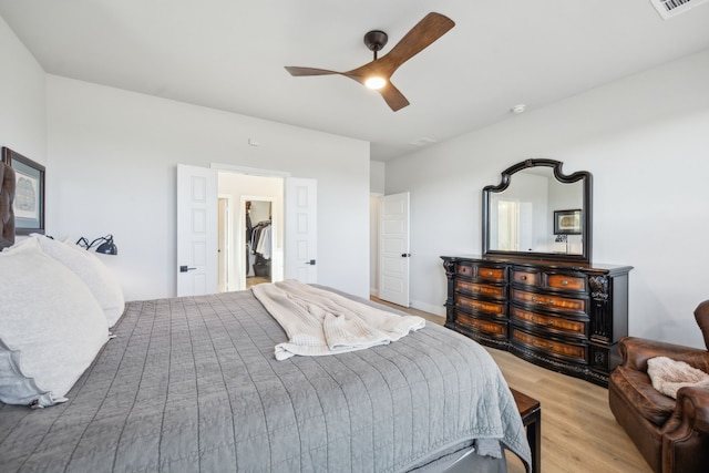 bedroom featuring ceiling fan, a spacious closet, and light wood-type flooring